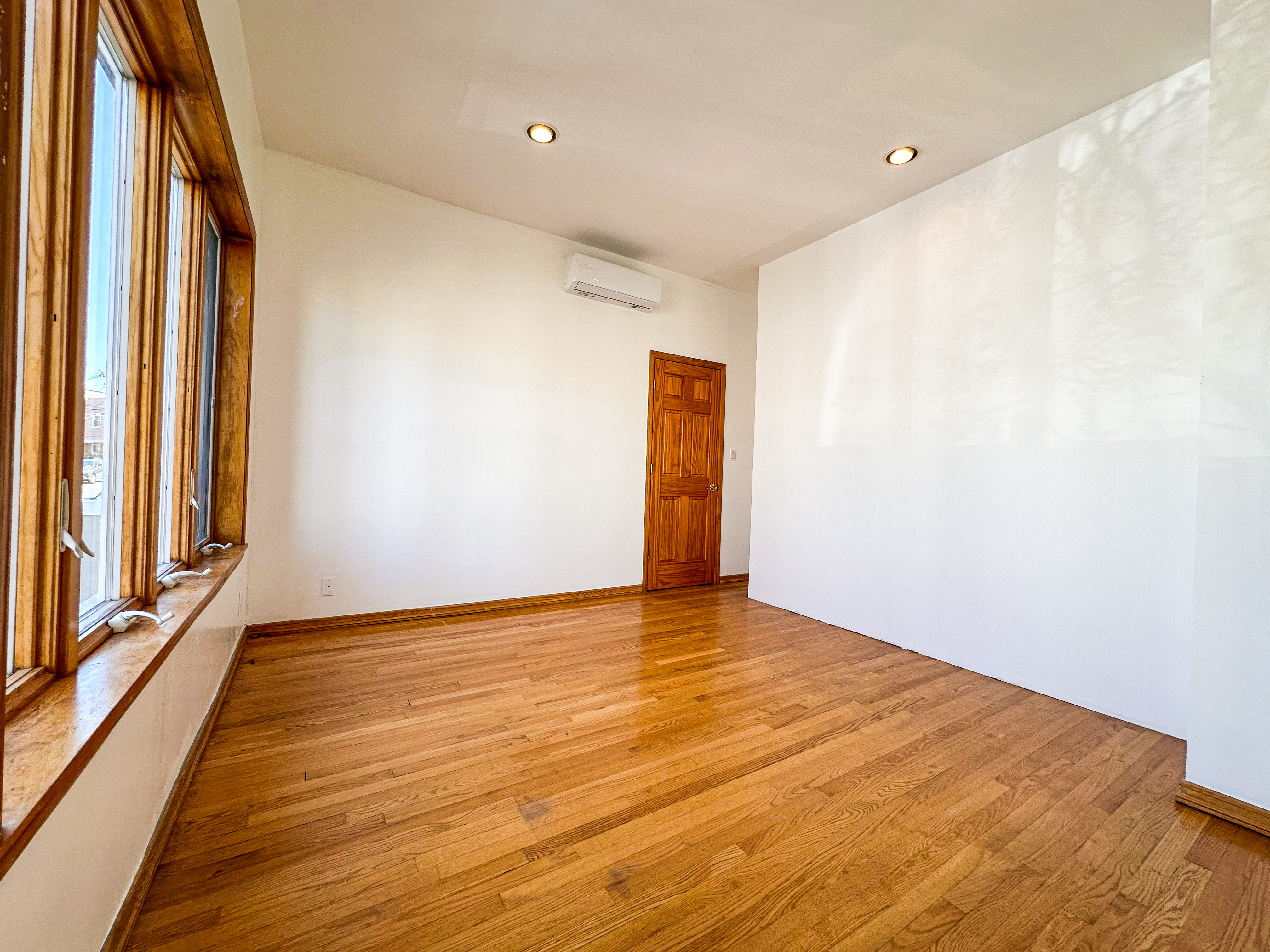 66-42 Clinton Avenue, Unit 2 Queens, NY 11378 - Photo 9 of 14 a view of an empty room with wooden floor and a window