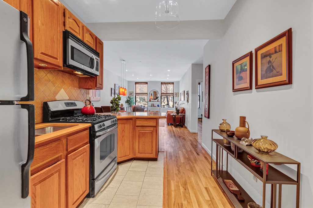 2322 Adam Clayton Powell Jr Boulevard, Unit 2G Manhattan, NY 10030 - Photo 4 of 8 a kitchen with stainless steel appliances granite countertop a stove top oven a sink dishwasher and cabinets with wooden floor