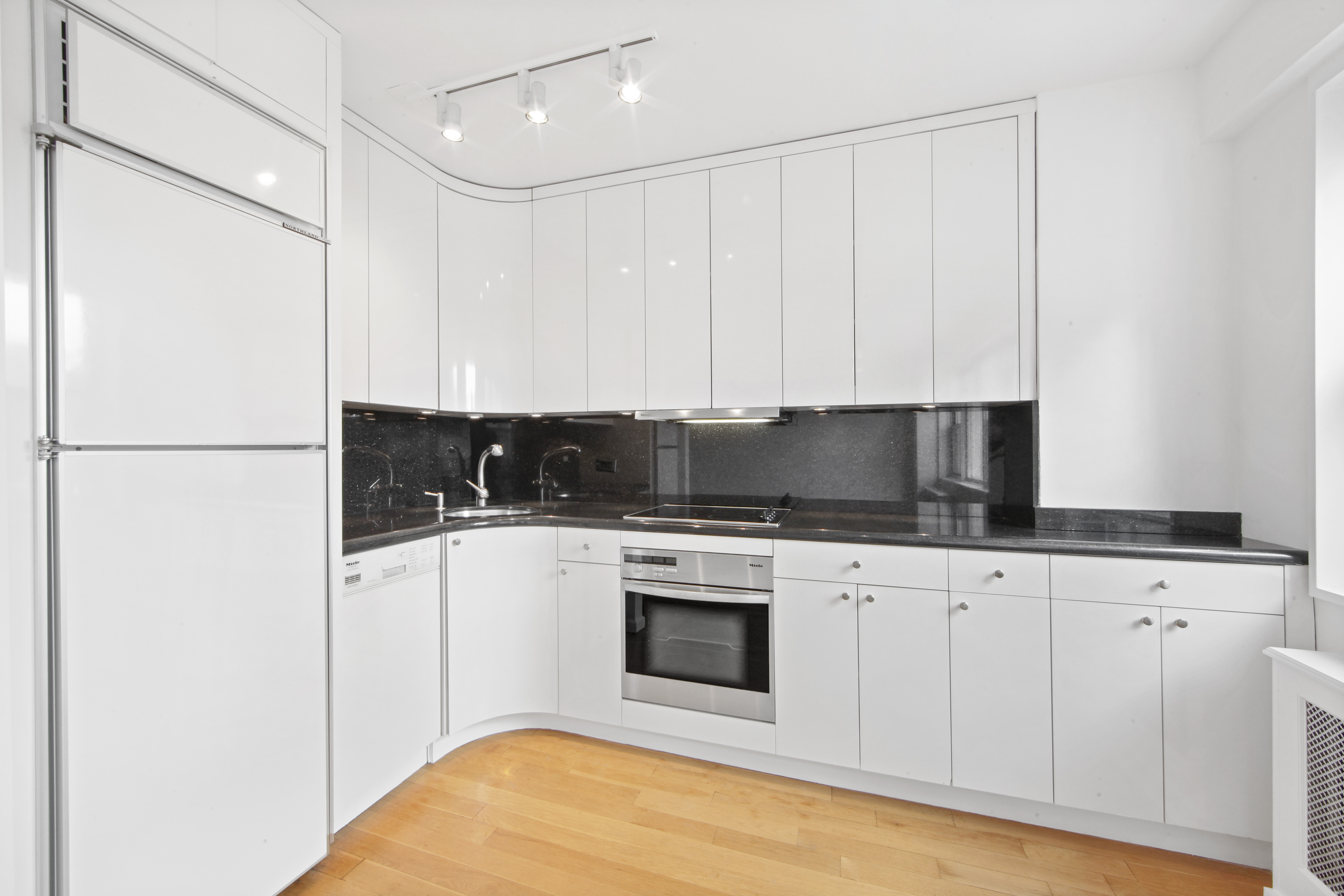 404 East 66th Street, Unit 11B Manhattan, NY 10065 - Photo 5 of 9 a kitchen with stainless steel appliances granite countertop a stove a refrigerator and white cabinets