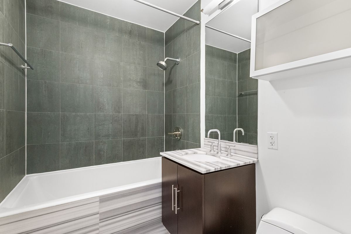 2-40 51st Avenue, Unit 2N Queens, NY 11101 - Photo 5 of 10 a bathroom with a granite countertop sink toilet and shower