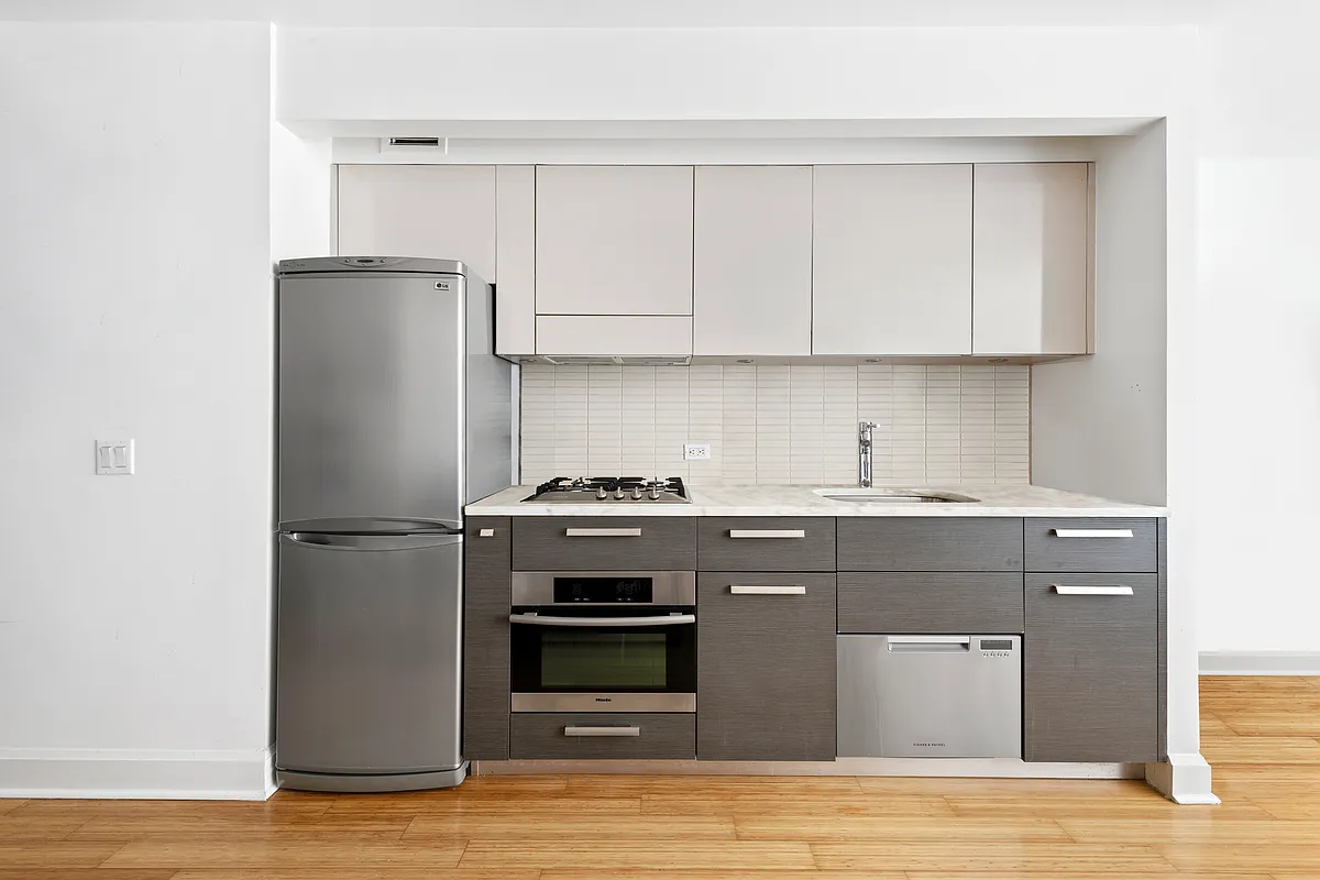 505 West 47th Street, Unit 2BS Manhattan, NY 10036 - Photo 3 of 5 a kitchen with stainless steel appliances granite countertop a refrigerator and a stove top oven