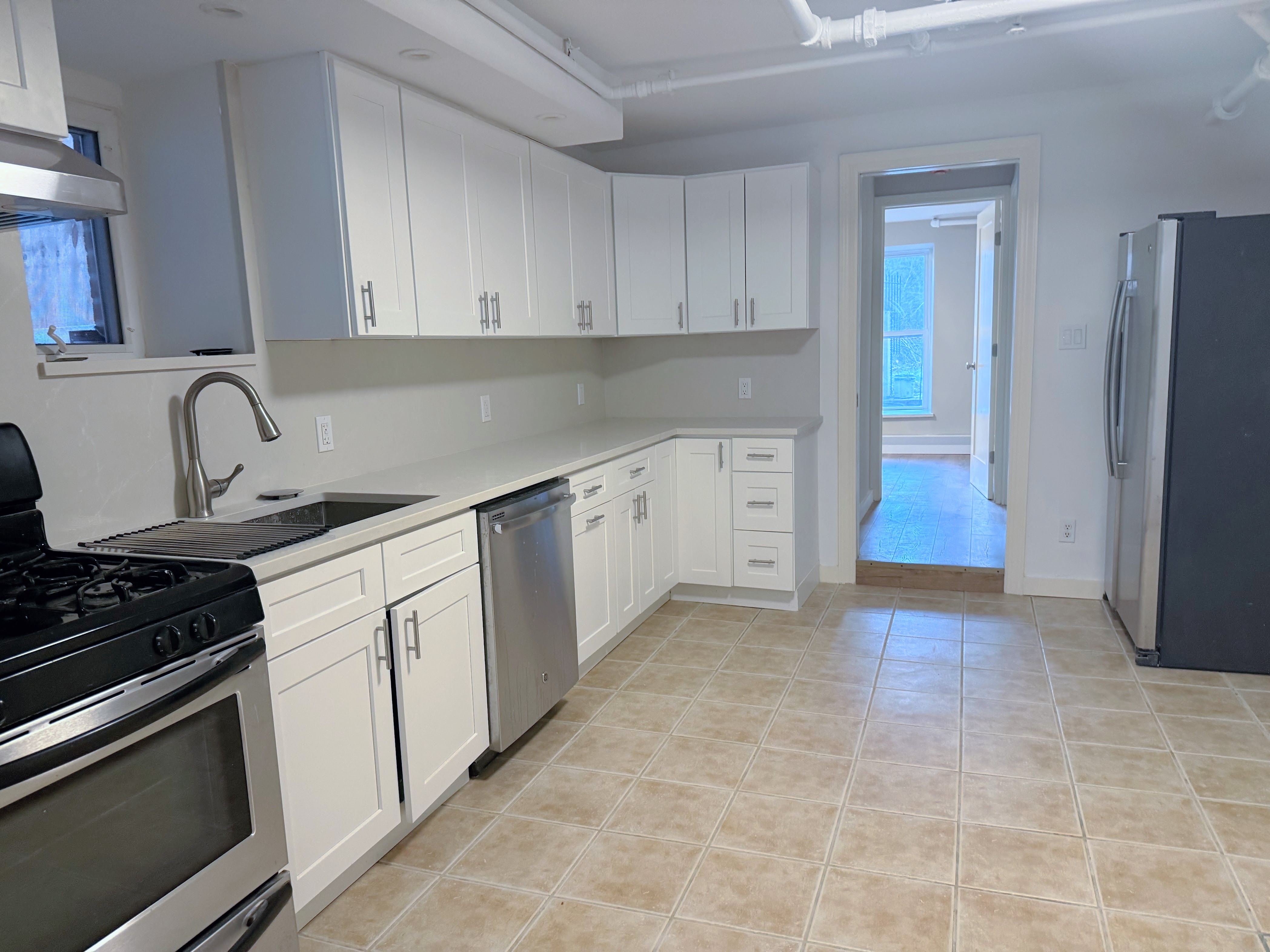 642 West 207th Street, Unit 1 Manhattan, NY 10034 - Photo 4 of 11 a kitchen with stainless steel appliances a sink stove and refrigerator