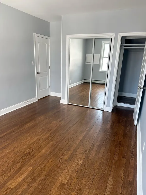 an empty room with wooden floor and mirror