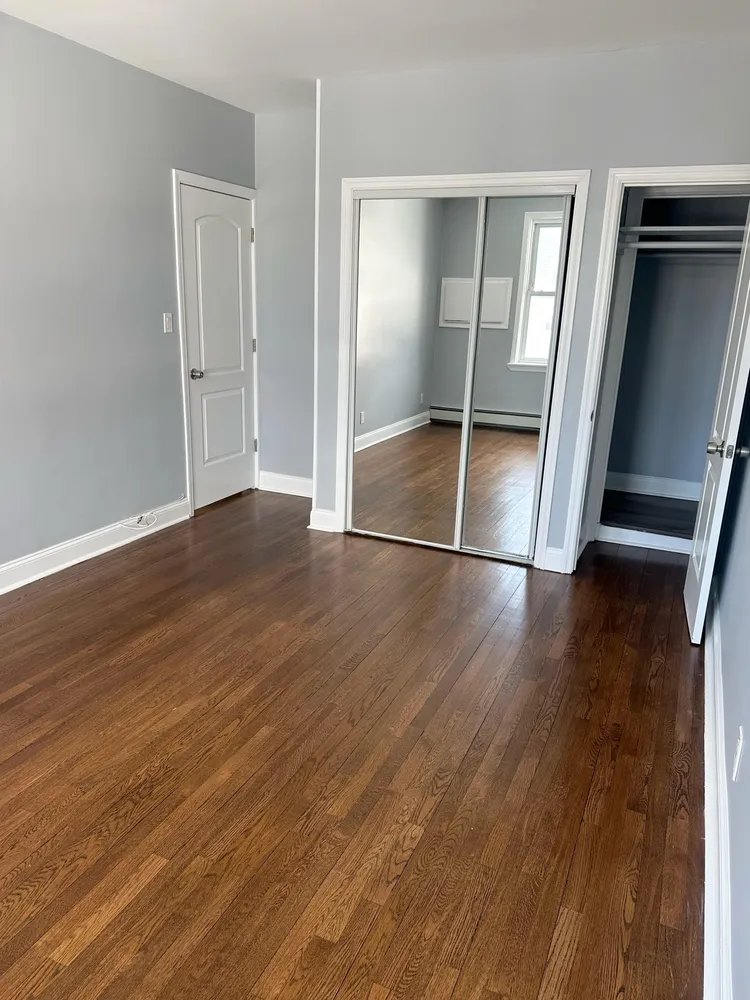 an empty room with wooden floor and mirror