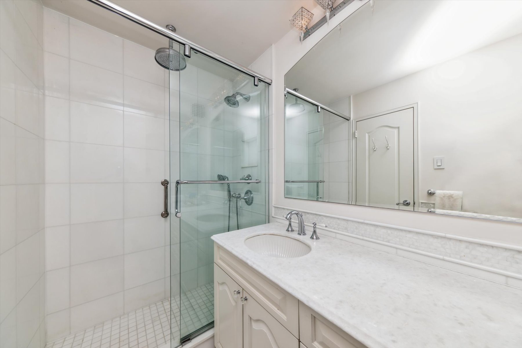 118 East 60th Street, Unit 33G Manhattan, NY 10022 - Photo 6 of 8 a bathroom with a granite countertop sink a shower and a mirror