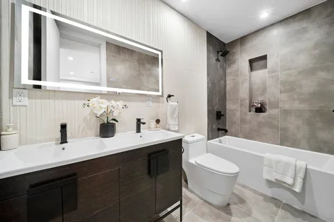a bathroom with a double vanity sink toilet mirror and bathtub