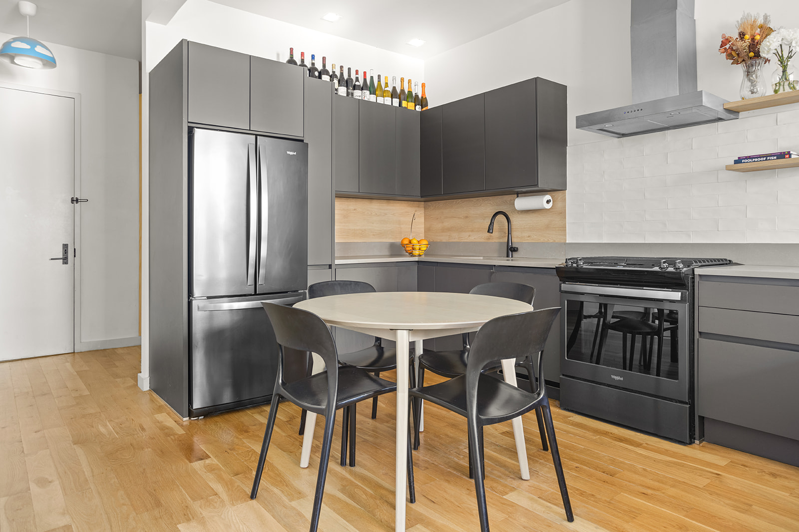 64 Stanhope Street, Unit 2A Brooklyn, NY 11221 - Photo 2 of 9 a kitchen with stainless steel appliances a dining table chairs and a refrigerator