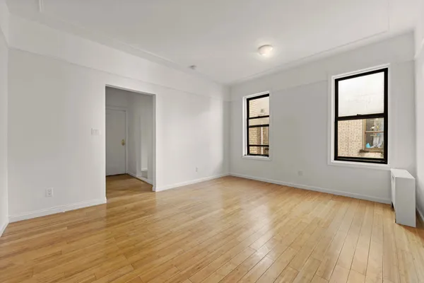 a view of an empty room with window and wooden floor