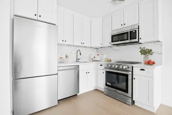 a kitchen with stainless steel appliances white cabinets and a refrigerator