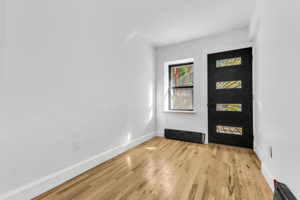 574 Gates Avenue Brooklyn, NY 11221 - Photo 8 of 16 a view of an empty room with window and wooden floor