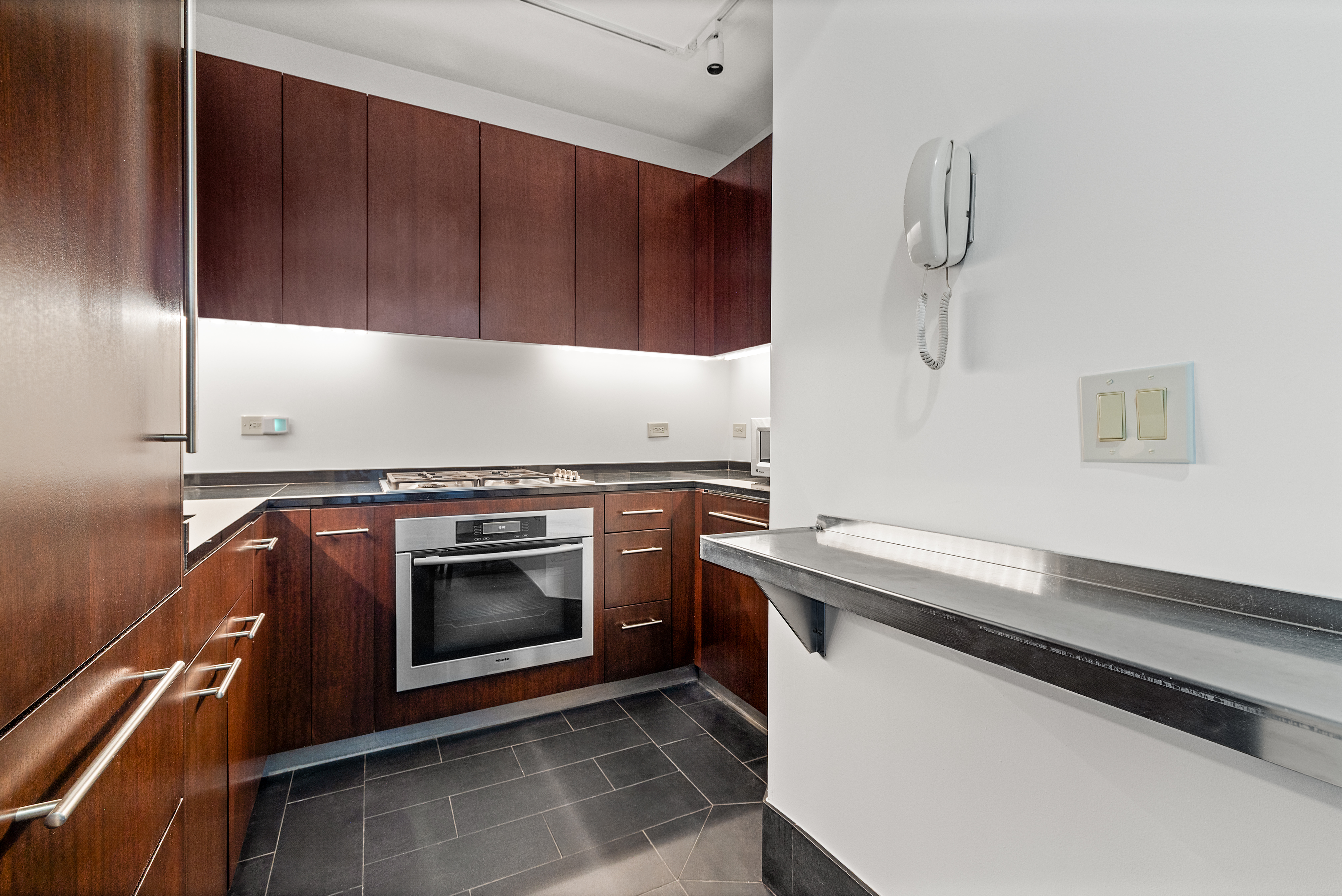 40 Broad Street, Unit 20C Manhattan, NY 10004 - Photo 4 of 20 a kitchen with granite countertop wood cabinets and stainless steel appliances