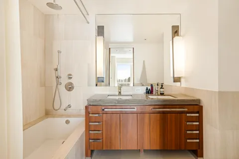 a bathroom with a granite countertop sink mirror and a bathtub