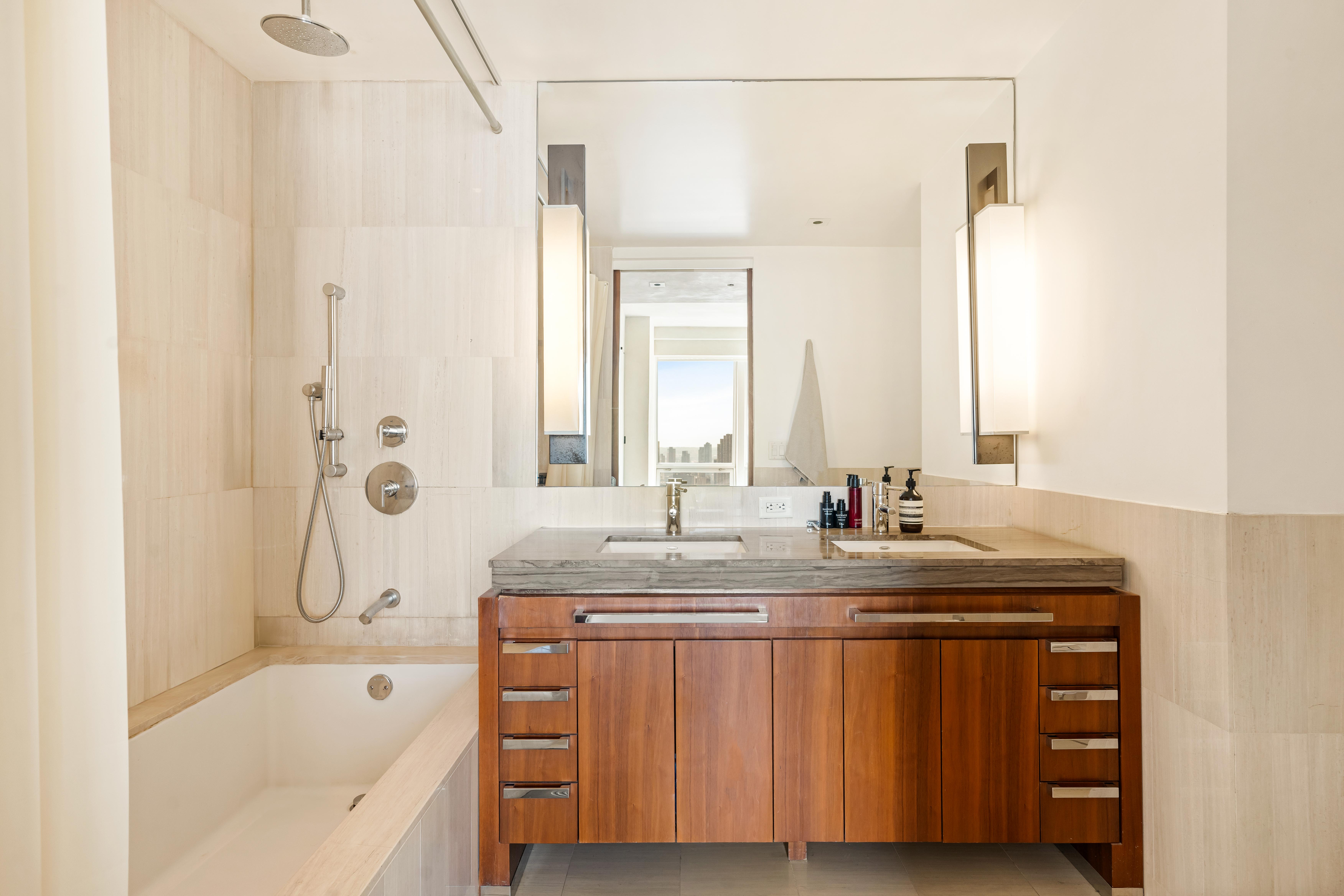 400 5th Avenue, Unit 45D Manhattan, NY 10018 - Photo 4 of 5 a bathroom with a granite countertop sink mirror and a bathtub