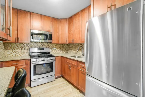 a kitchen with stainless steel appliances granite countertop a refrigerator a stove a sink and dishwasher