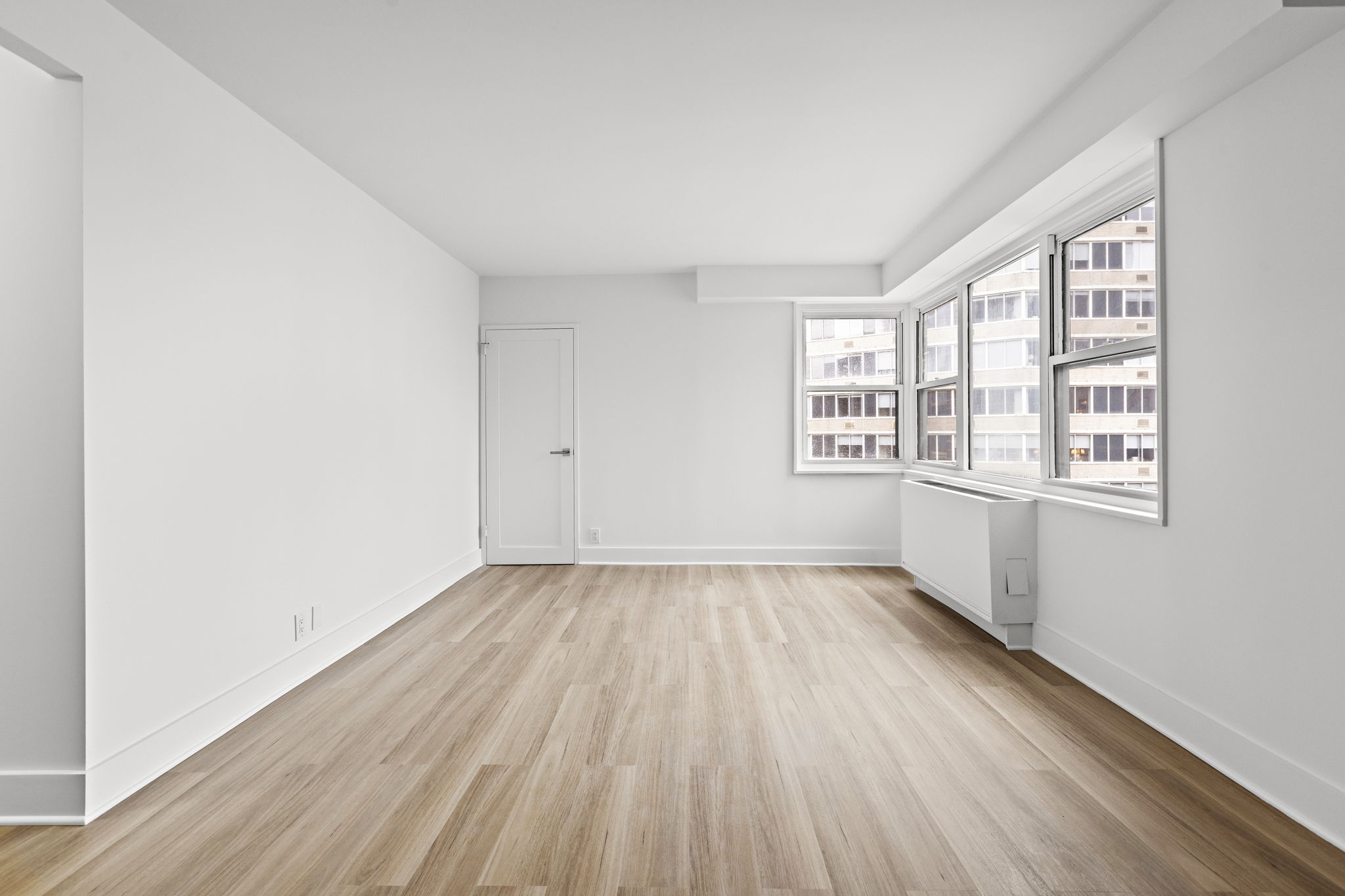 400 East 54th Street, Unit 19H Manhattan, NY 10022 - Photo 13 of 15 an empty room with wooden floor and windows