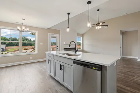 a kitchen with a sink a center island and wooden floor