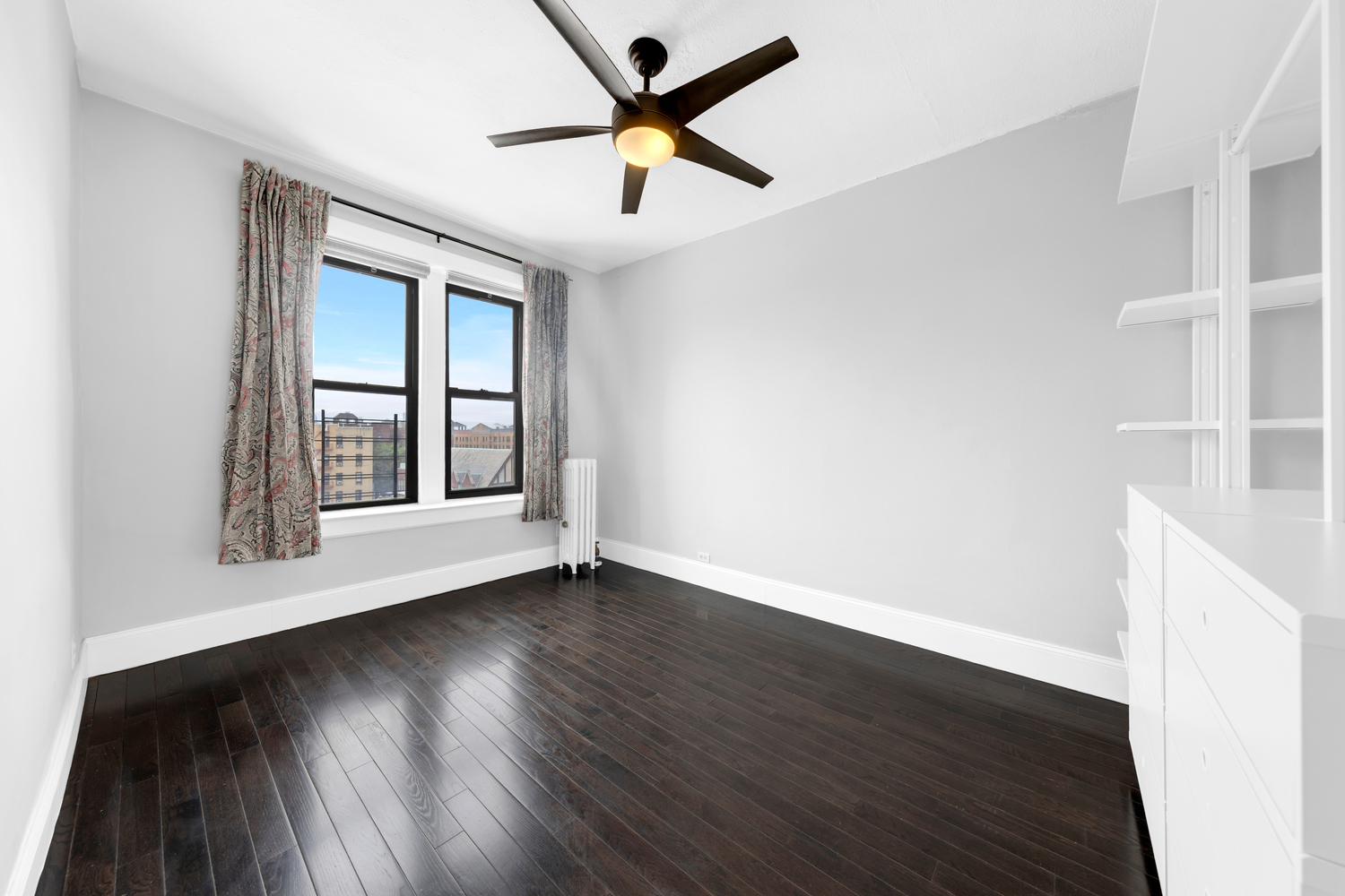 37-20 83rd Street, Unit 6J Queens, NY 11372 - Photo 10 of 14 an empty room with wooden floor and windows