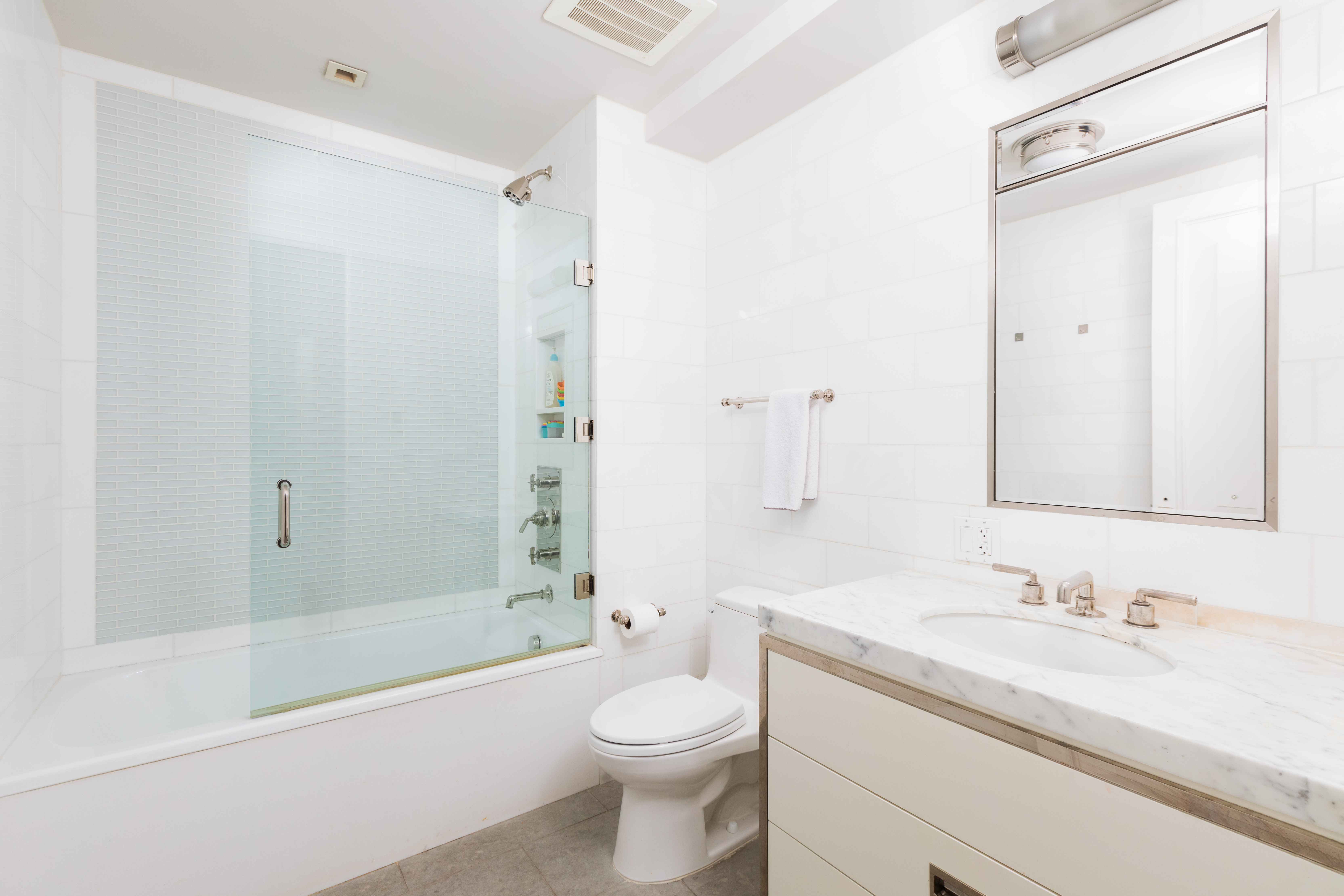 141 East 88th Street, Unit 5 Manhattan, NY 10128 - Photo 7 of 12 a bathroom with a granite countertop sink toilet and shower