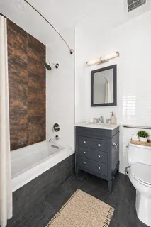 a bathroom with a tub sink double vanity and mirror