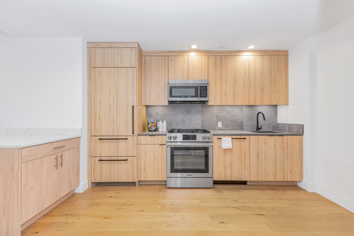 24-16 Queens Plaza South, Unit 4J Queens, NY 11101 - Photo 3 of 15 a kitchen with stainless steel appliances granite countertop a stove a sink and a refrigerator