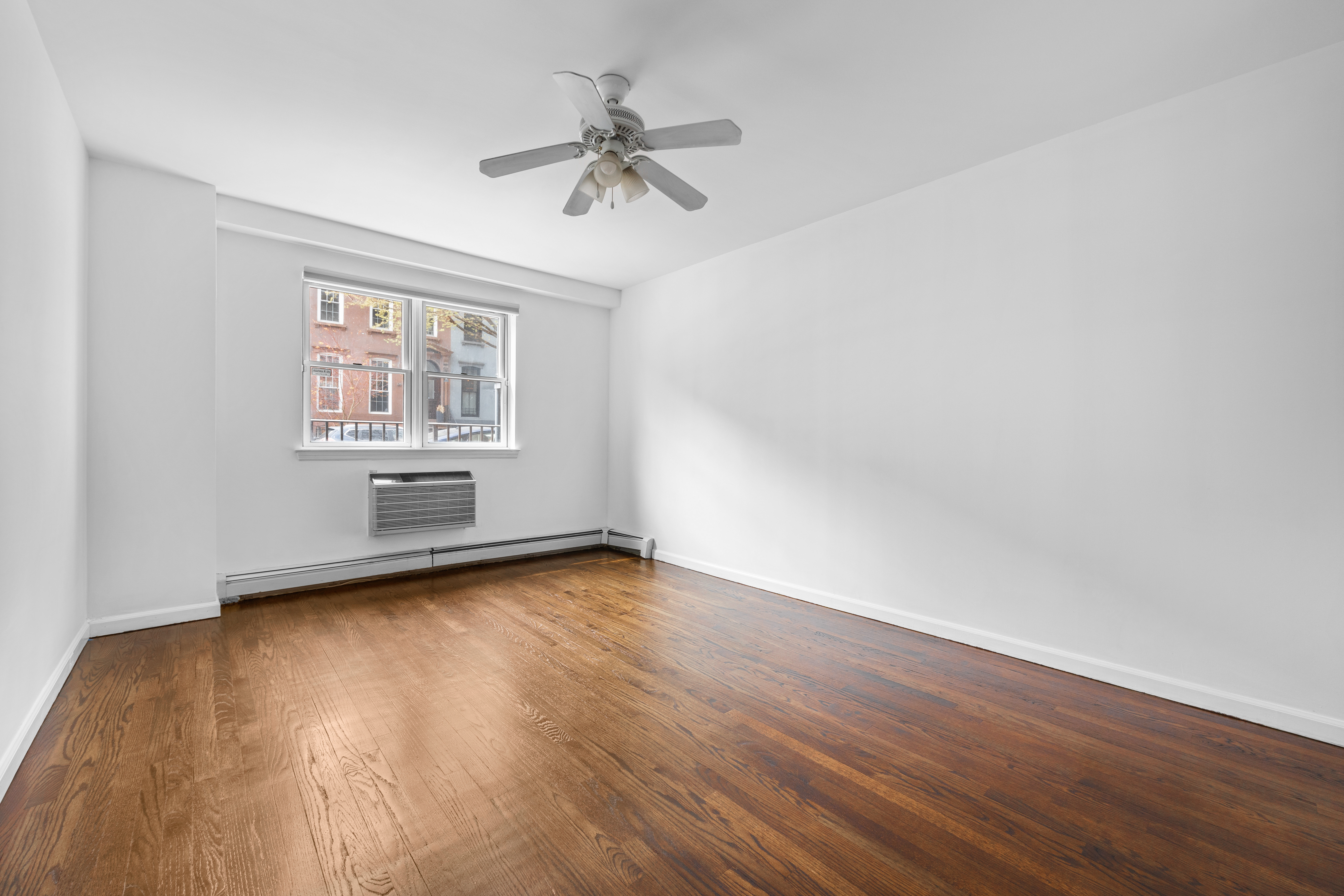125 Bergen Street, Unit 1A Brooklyn, NY 11201 - Photo 7 of 9 an empty room with wooden floor chandelier fan and windows