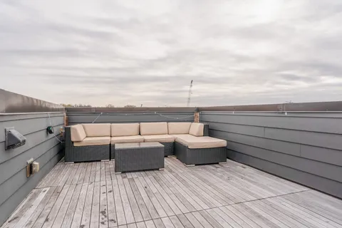 a view of roof deck with couches and wooden floor
