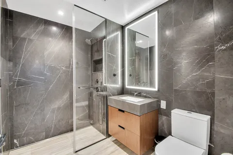 a bathroom with a granite countertop sink toilet and shower