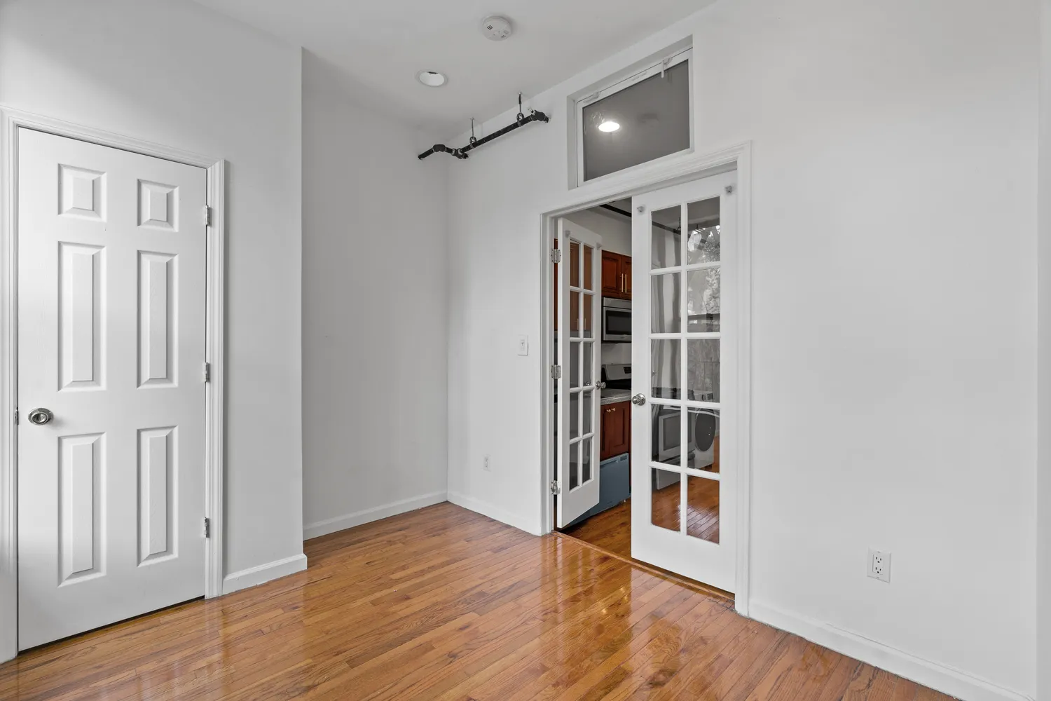 an empty room with wooden floor closet and windows
