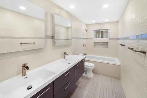 a bathroom with a double vanity sink toilet and a tub