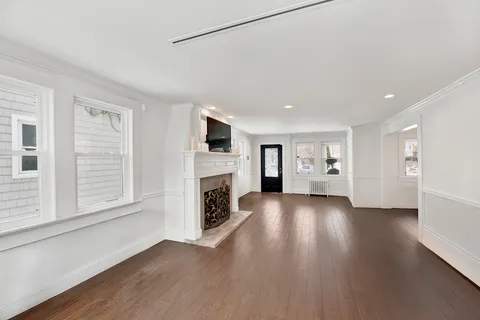 a view of empty room with wooden floor and fireplace