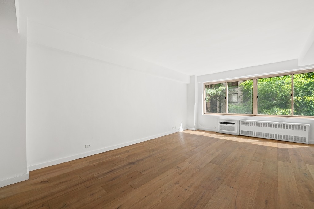 225 East 46th Street, Unit 2G Manhattan, NY 10017 - Photo 2 of 6 an empty room with wooden floor and windows