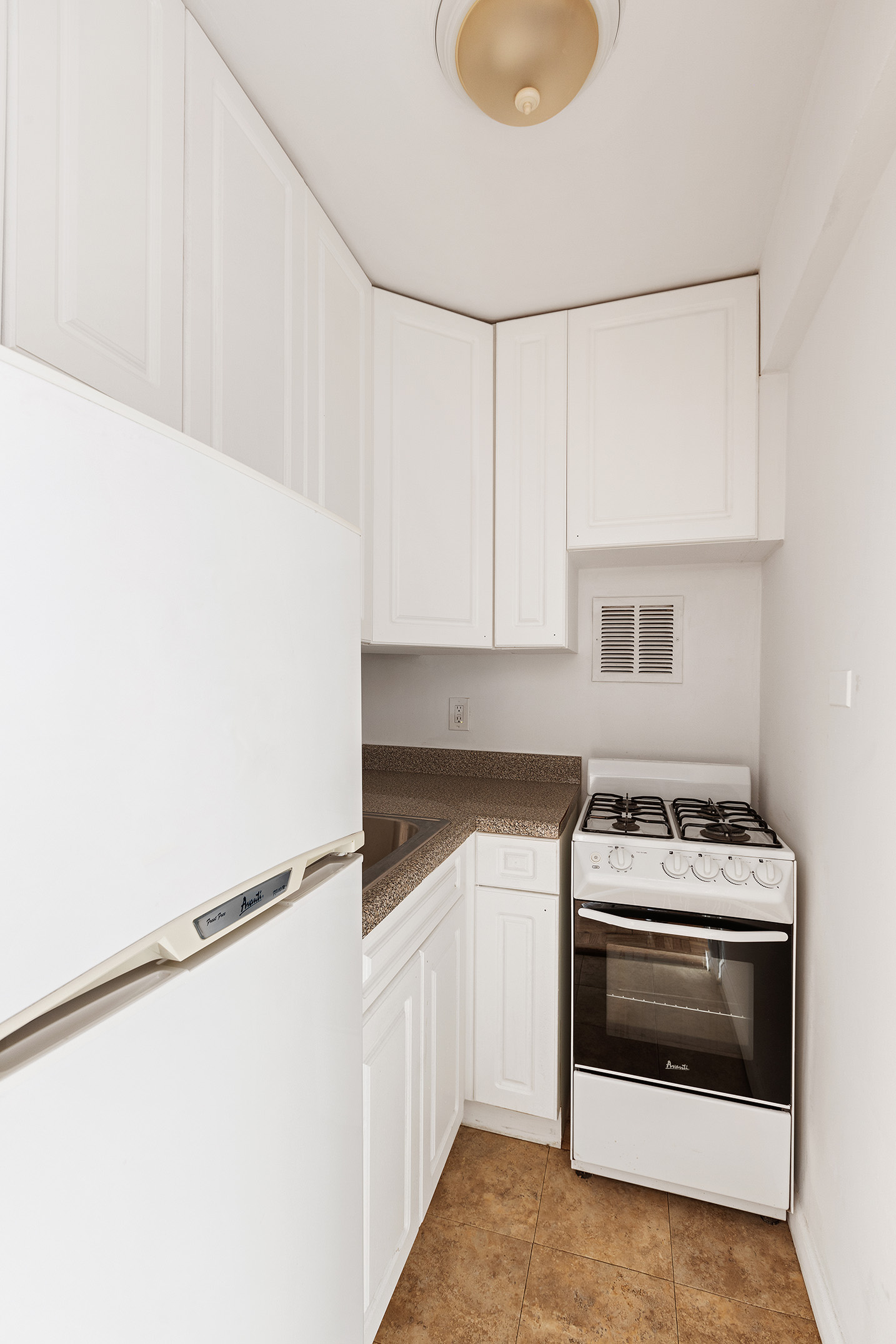 335 East 51st Street, Unit 6G Manhattan, NY 10022 - Photo 9 of 12 a kitchen with granite countertop white cabinets and white appliances