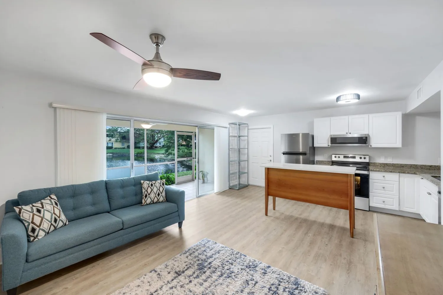 a living room with stainless steel appliances granite countertop furniture and a large window