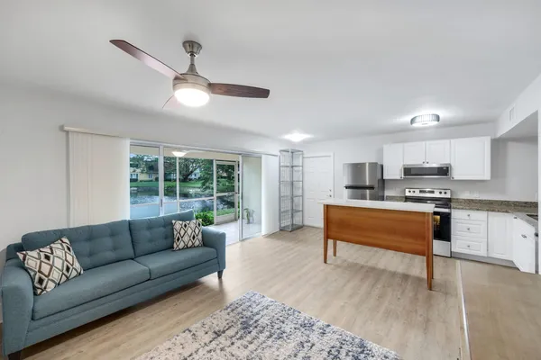 a living room with stainless steel appliances granite countertop furniture and a large window