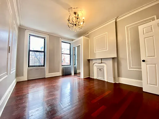 a view of an empty room with a window and wooden floor