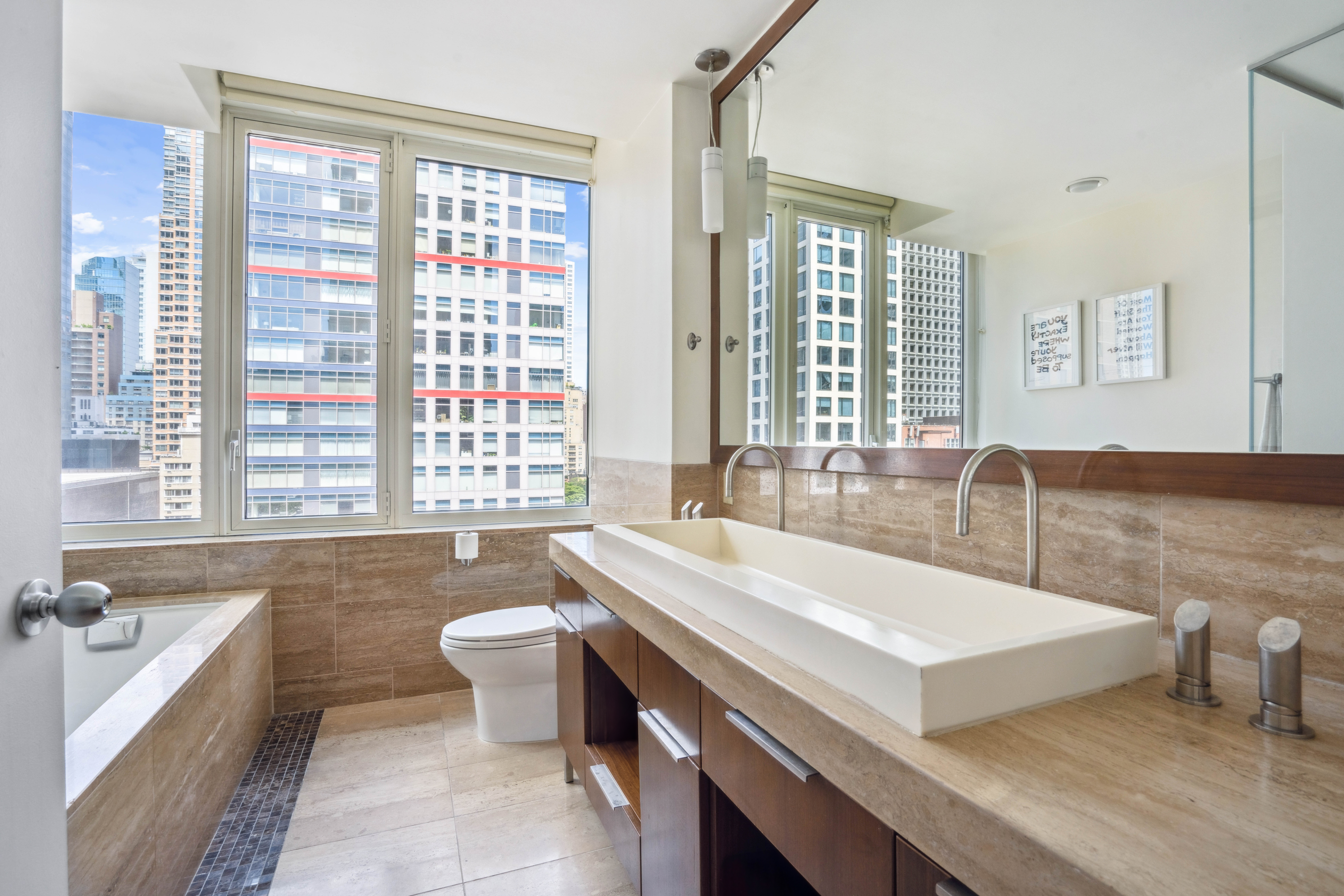250 East 53rd Street, Unit 1402 Manhattan, NY 10022 - Photo 6 of 13 a bathroom with a tub a sink and a large window