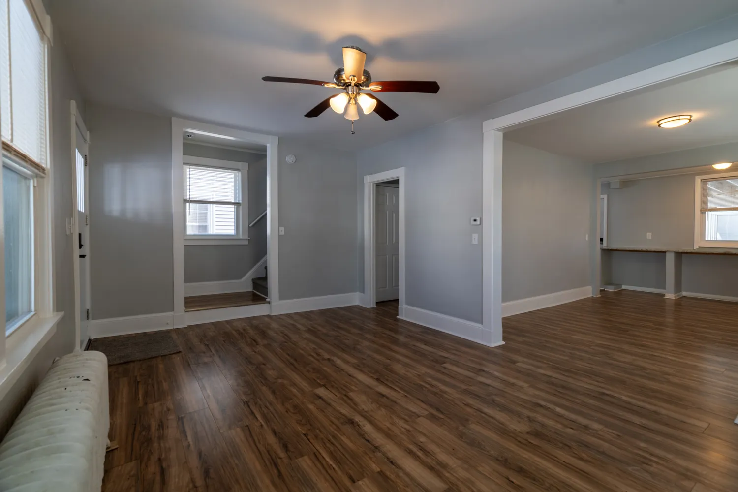 a view of an empty room with wooden floor and a window