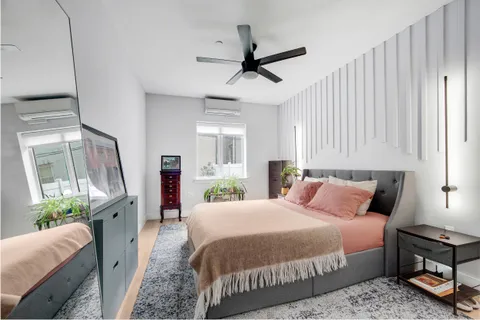 a bedroom with a bed flat screen tv and a large window