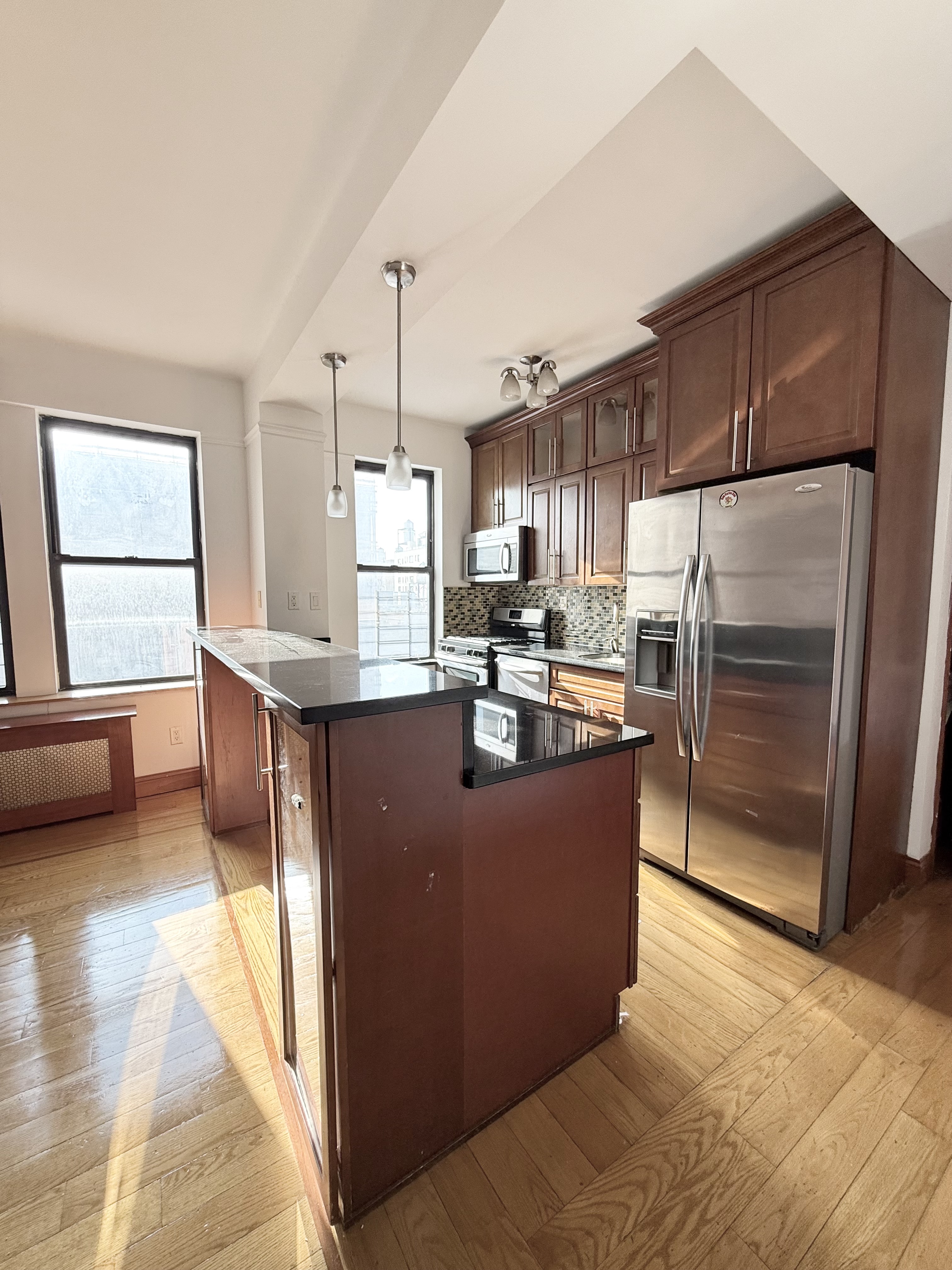 675 West End Avenue, Unit 12A Manhattan, NY 10025 - Photo 5 of 15 a kitchen with kitchen island granite countertop wooden cabinets a refrigerator and a stove