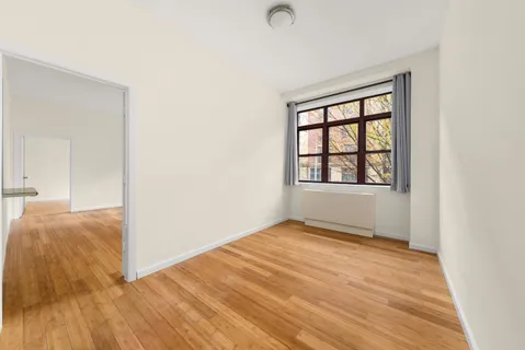 an empty room with wooden floor cabinet and windows
