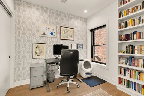 a view of a workspace with furniture and a book shelf