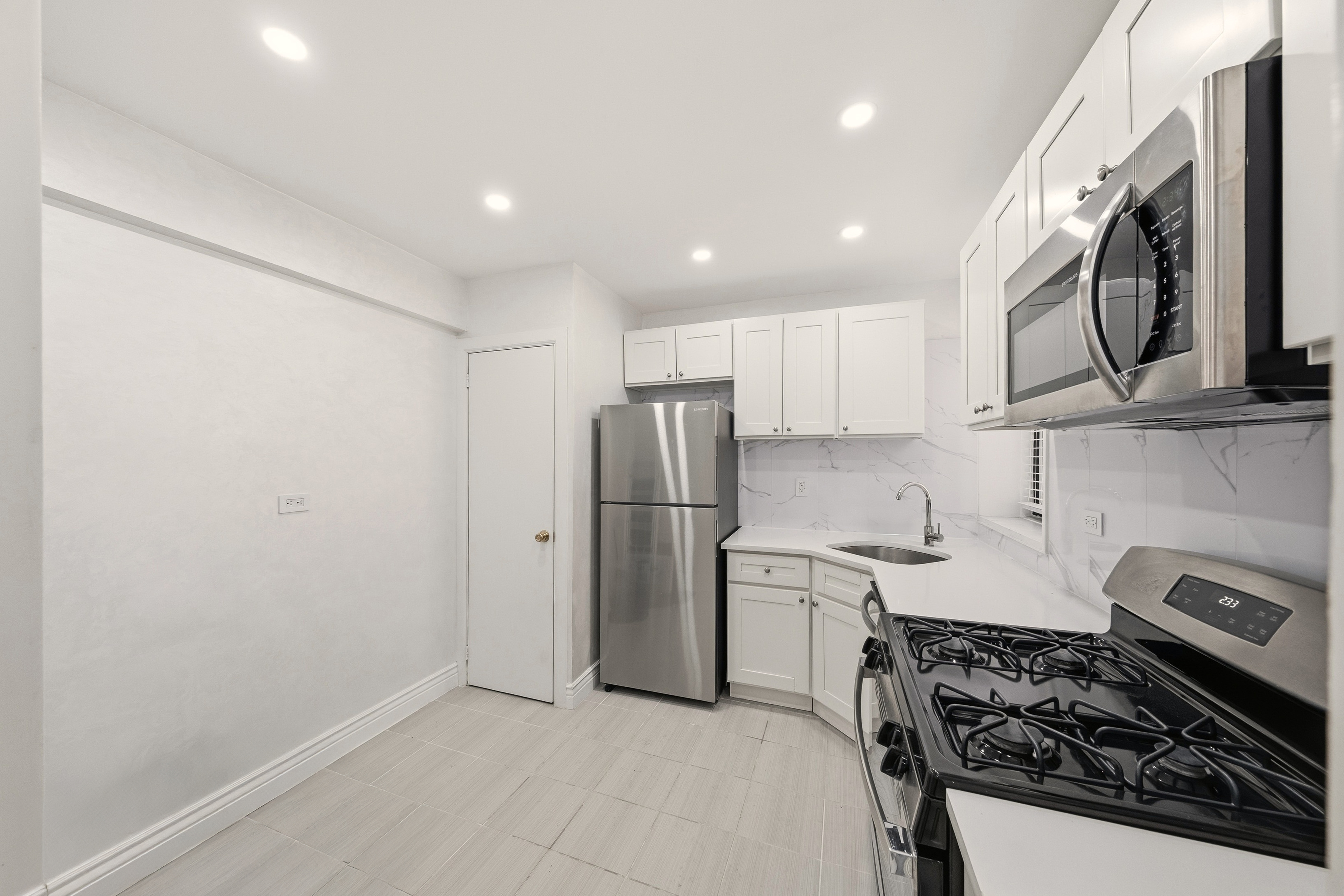 1577 East 17th Street, Unit 2F Brooklyn, NY 11230 - Photo 8 of 21 a kitchen with stainless steel appliances granite countertop a stove a refrigerator and a microwave