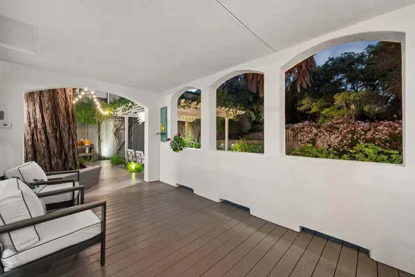 a view of a patio with table and chairs potted plants and floor to ceiling window