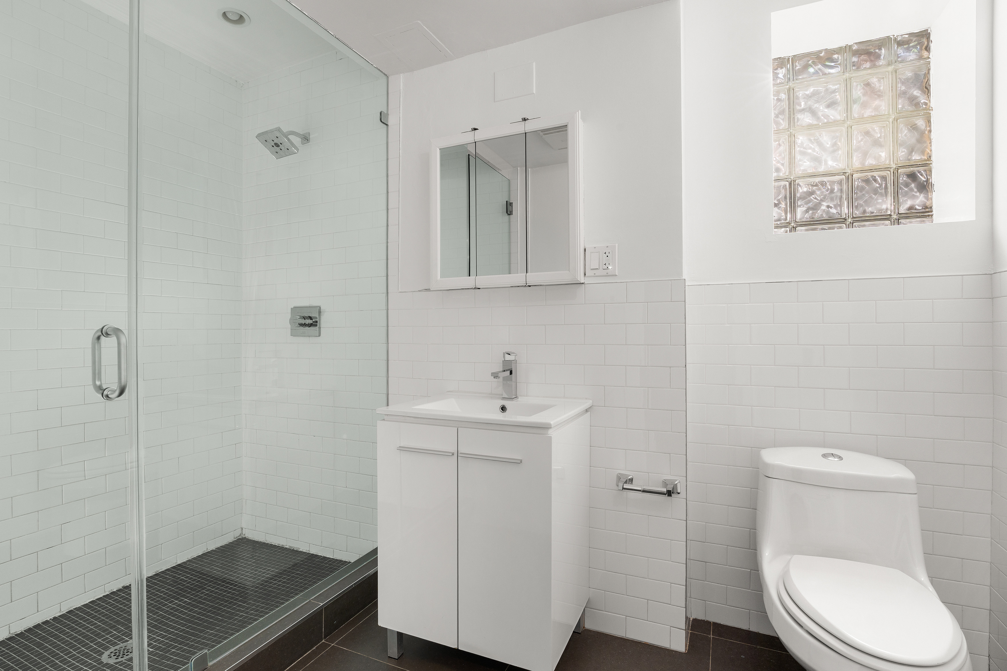 71 Irving Place, Unit 1 Brooklyn, NY 11238 - Photo 7 of 14 a bathroom with a toilet a sink a vanity and mirror