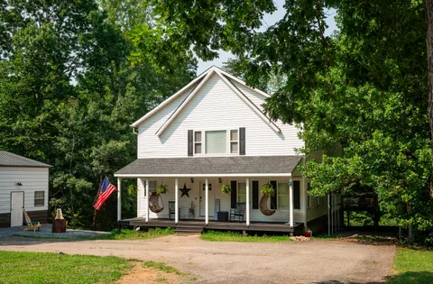 a view of a white house with large windows and a small yard