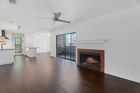 a view of an empty room with wooden floor fireplace and a window