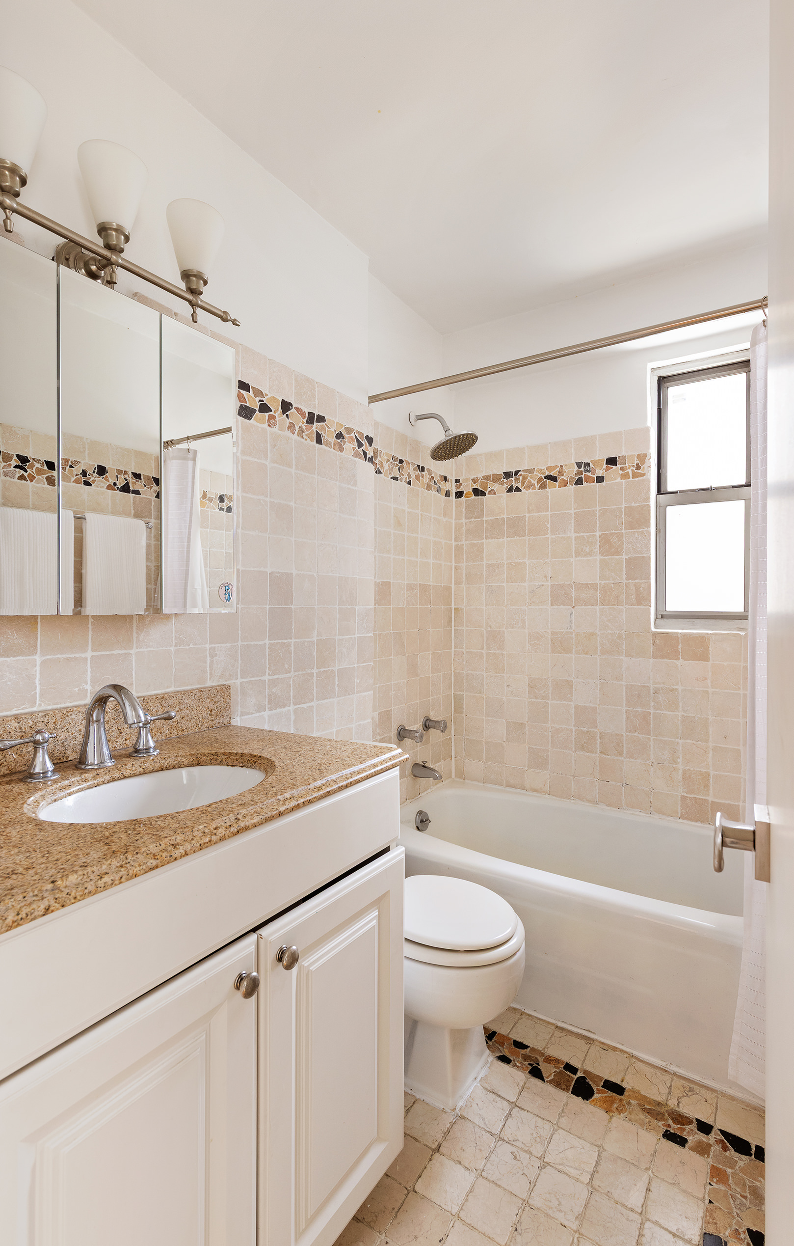 525 East 82nd Street, Unit 12E Manhattan, NY 10028 - Photo 19 of 29 a bathroom with a granite countertop sink a toilet a mirror a bathtub and shower