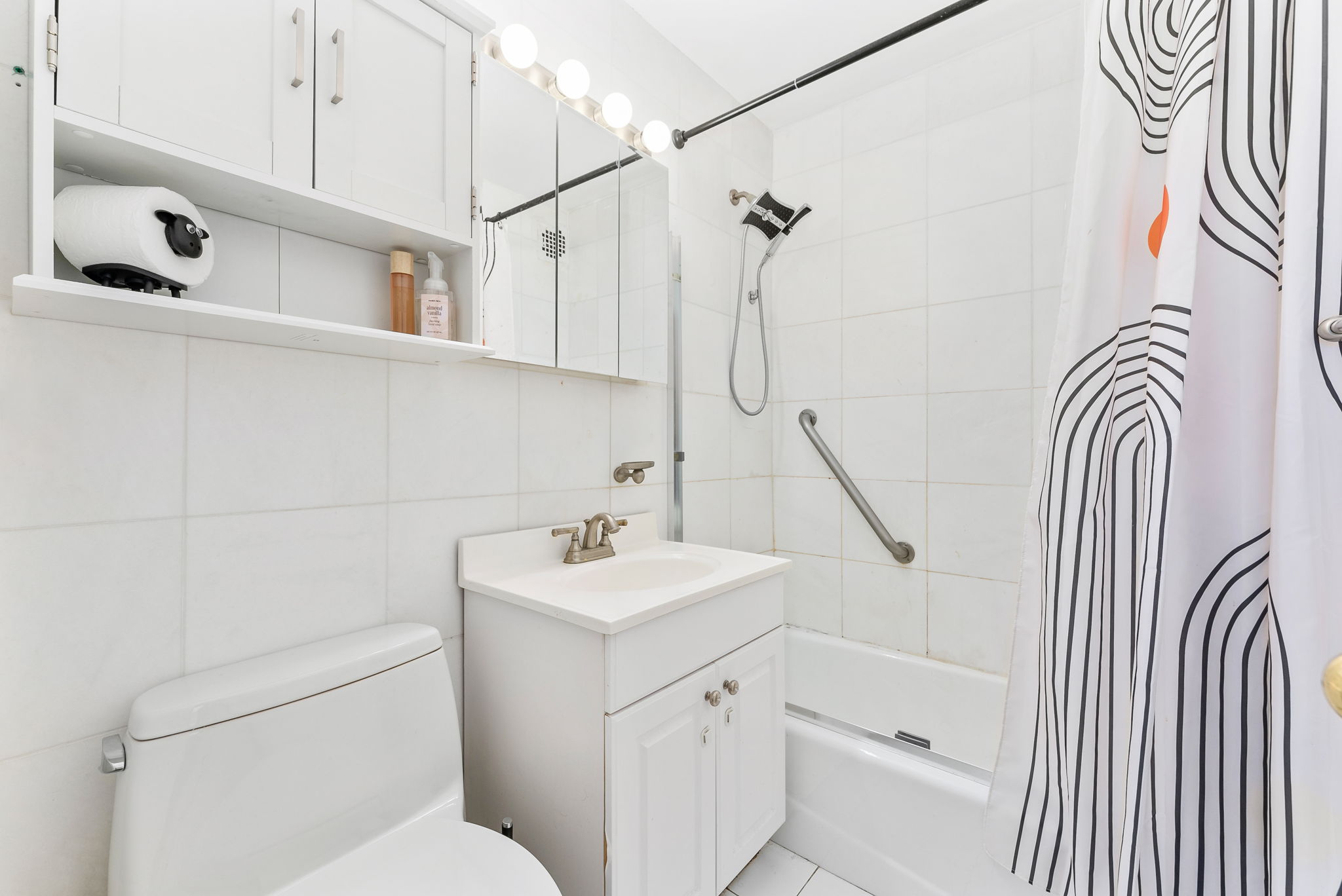 40 Sutton Place, Unit 9J Manhattan, NY 10022 - Photo 5 of 11 a bathroom with a sink a toilet and shower curtain