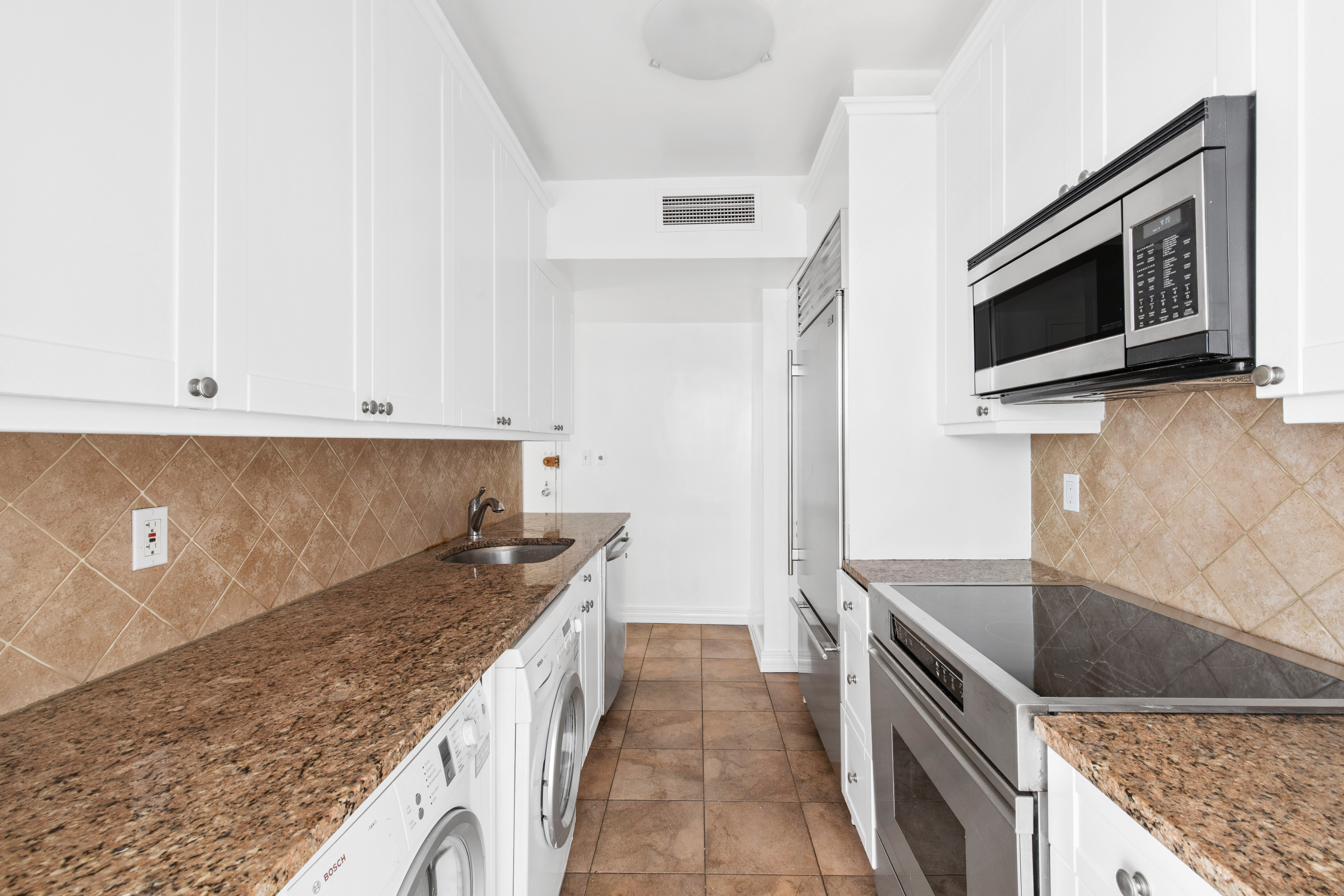201 East 62nd Street, Unit 2C Manhattan, NY 10065 - Photo 8 of 14 a kitchen with granite countertop a sink and stainless steel appliances