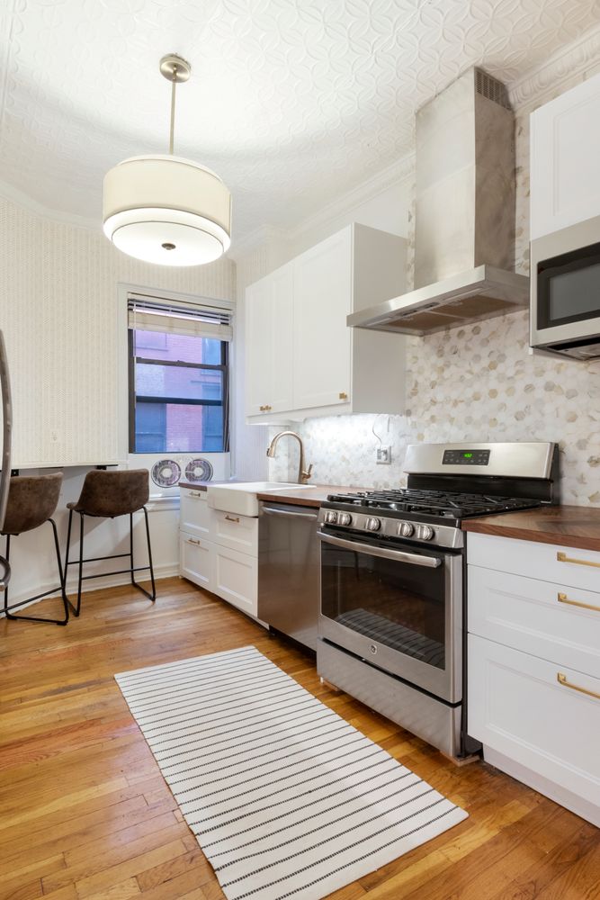 31 Tiemann Place, Unit 37 Manhattan, NY 10027 - Photo 5 of 10 a kitchen with stainless steel appliances granite countertop a stove a sink and a microwave